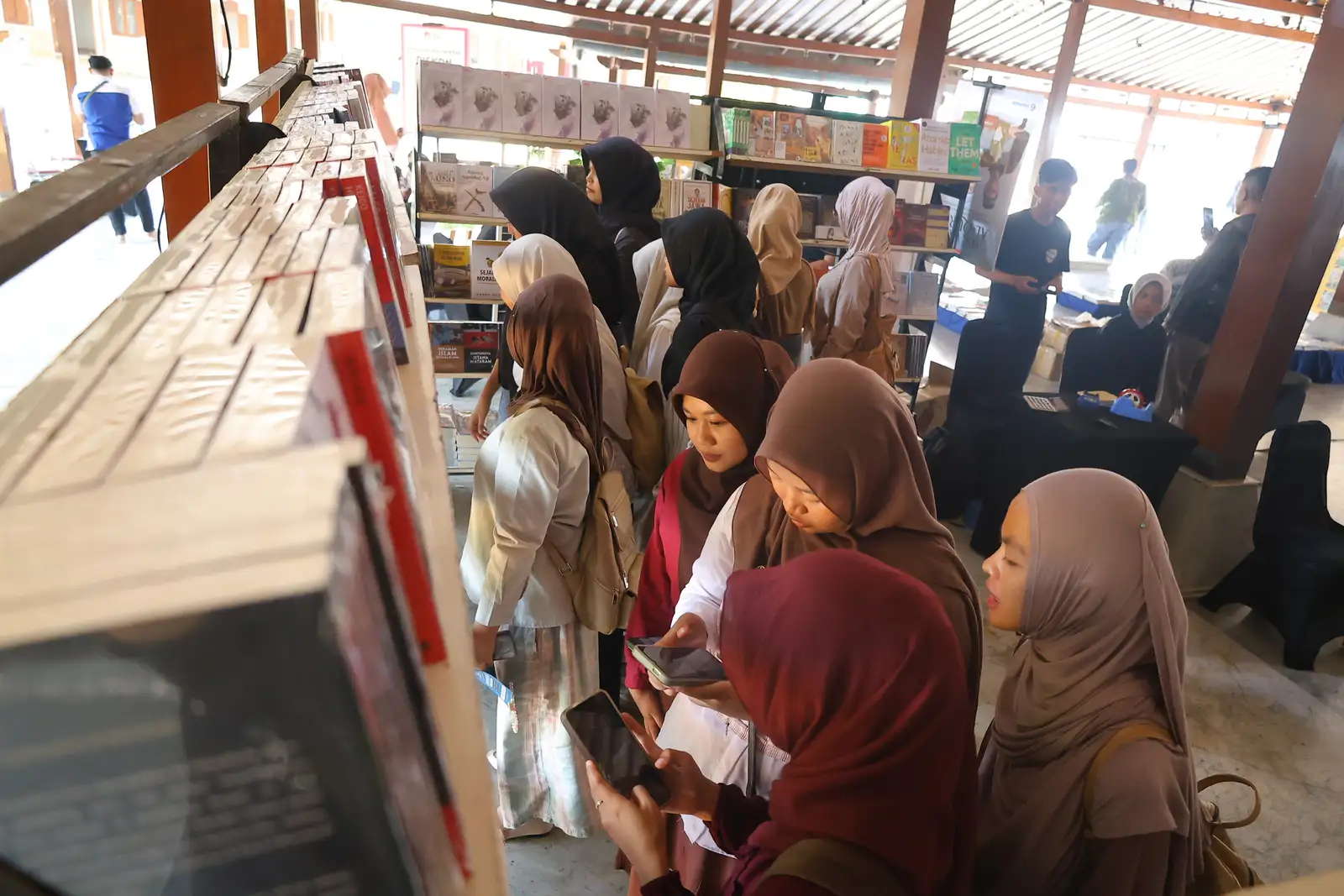 Pengunjung festival literasi sedang melihat-lihat dan memilih buku di rak pameran Ndalem Djojokoesoeman. 