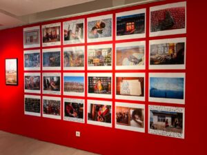 Deretan karya fotografi dipajang pada dinding merah di ruang pameran