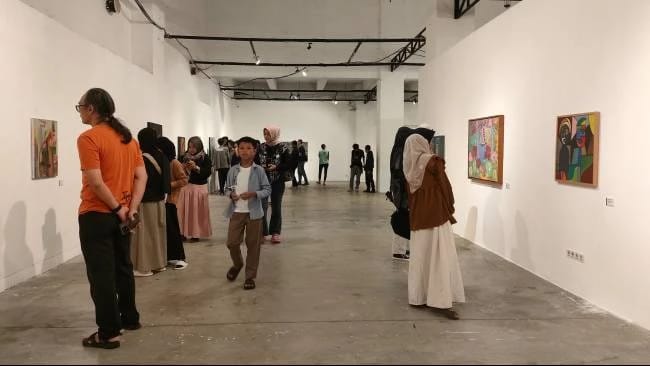 Pengunjung mengamati berbagai lukisan yang dipajang di dinding galeri pameran seni indoor.