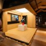 Booth pameran berstruktur kayu modern dengan patung seni di atas panggung kayu.