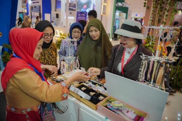 Sekelompok pengunjung wanita sedang melihat dan memilih produk aksesoris kerajinan tangan di stan pameran.