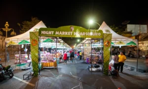 Gerbang masuk Night Market Ngarsopuro bernuansa hijau-batik dengan latar deretan tenda pedagang UMKM di malam hari.