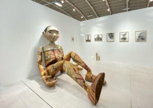 Instalasi patung figur manusia berukuran besar yang duduk di dinding galeri pameran seni kontemporer Art Jakarta 2026 di JIExpo Kemayoran.