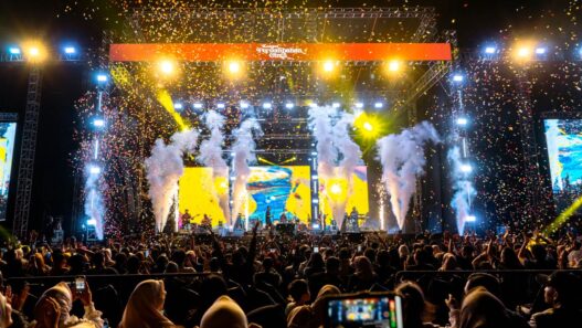 Panggung konser musik megah dengan efek kembang api dan konfeti bertuliskan Konser Persembahan Cinta.