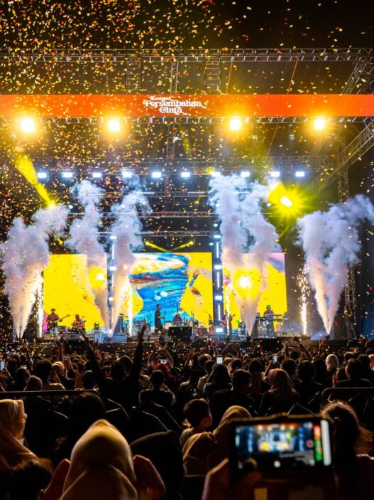 Panggung konser musik megah dengan efek kembang api dan konfeti bertuliskan Konser Persembahan Cinta.