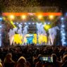 Panggung konser musik megah dengan efek kembang api dan konfeti bertuliskan Konser Persembahan Cinta.