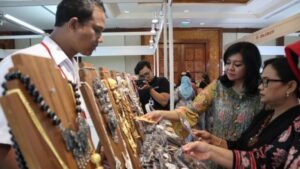 Dua wanita sedang melihat perhiasan di stand pameran.