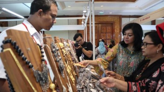 Dua wanita sedang melihat perhiasan di stand pameran.