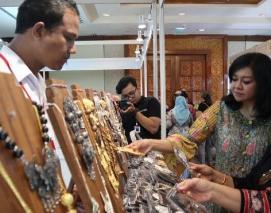 Dua wanita sedang melihat perhiasan di stand pameran.