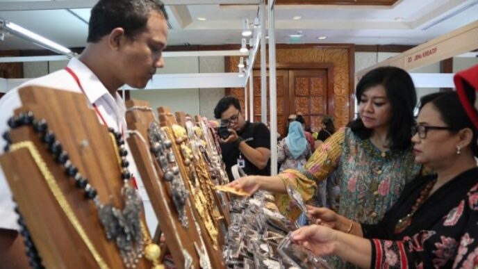 Dua wanita sedang melihat perhiasan di stand pameran.