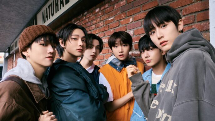 Enam anggota boyband K-pop BOYNEXTDOOR berpose gaya casual streetwear di luar ruangan dengan latar belakang dinding bata merah.