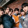 Enam anggota boyband K-pop BOYNEXTDOOR berpose gaya casual streetwear di luar ruangan dengan latar belakang dinding bata merah.