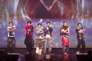 Enam anggota grup K-pop ENHYPEN tampil enerjik dan membawakan koreografi di atas panggung konsert di depan layar LED besar.