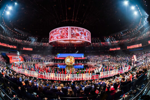Suasana megah stadium dalam panggung pembukaan WorldSkills Shanghai 2026 yang dipenuhi bendera peserta dan layar silinder besar bertuliskan China.