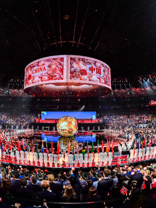 Suasana megah stadium dalam panggung pembukaan WorldSkills Shanghai 2026 yang dipenuhi bendera peserta dan layar silinder besar bertuliskan China.
